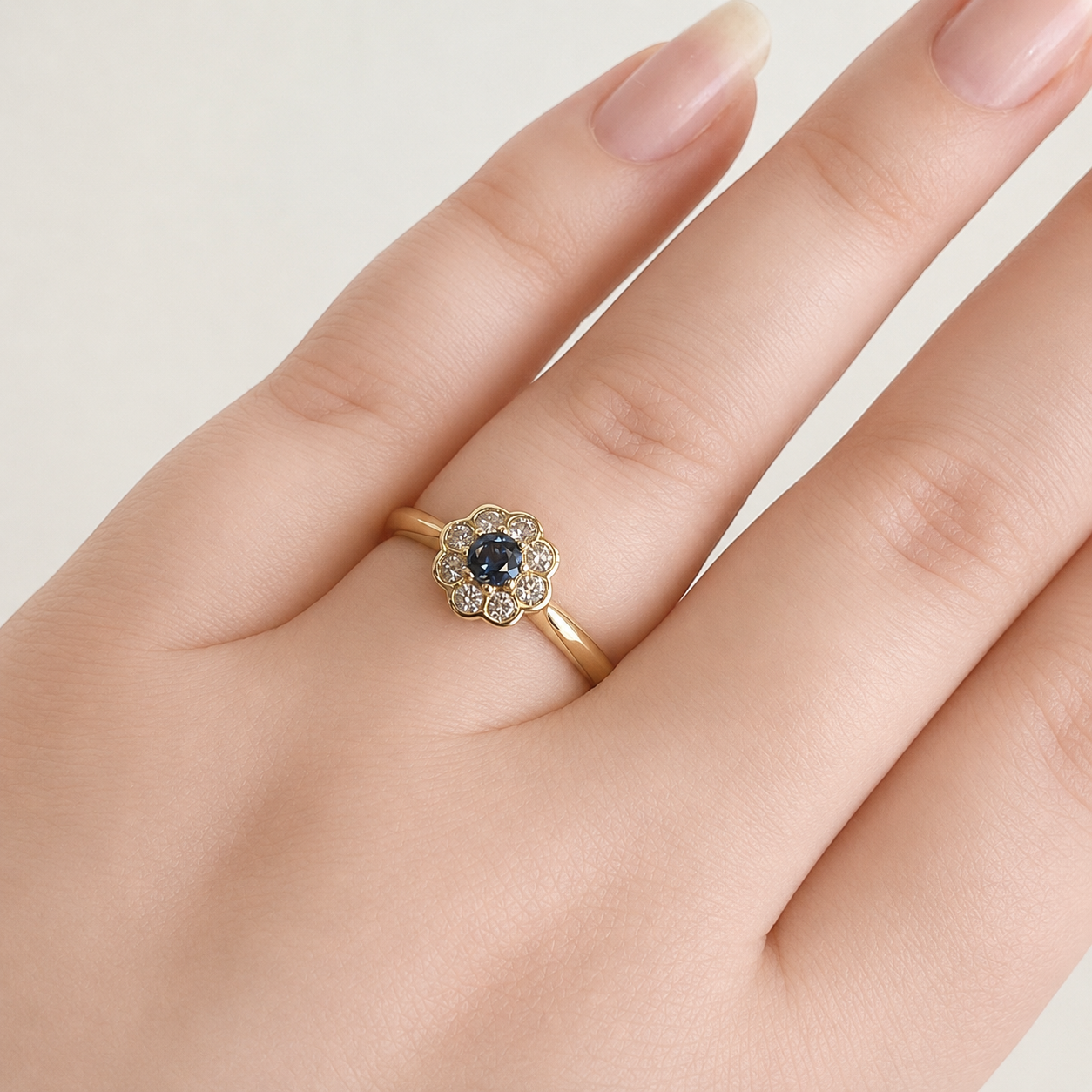 Gold ring with a central black gemstone and diamond accents on a hand against a light background