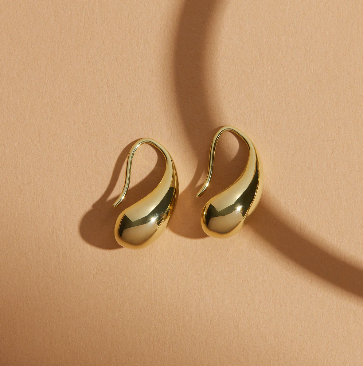 Gold earrings on a beige background