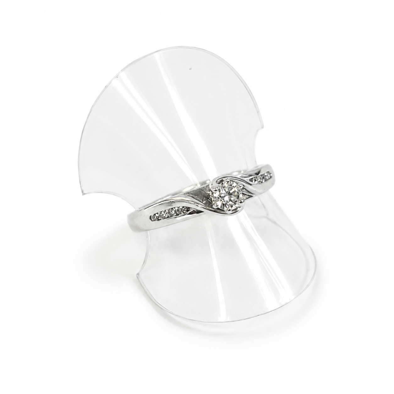 white gold ring with a diamond on a clear stand against a white background