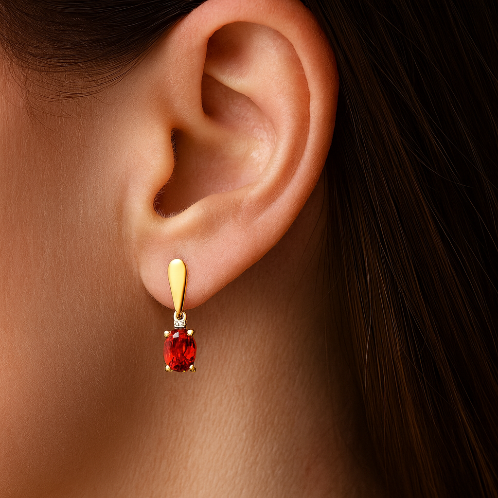 Gold earring with a red gemstone worn by a person