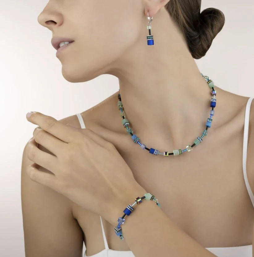 Woman wearing a colorful beaded necklace and bracelet on a plain background