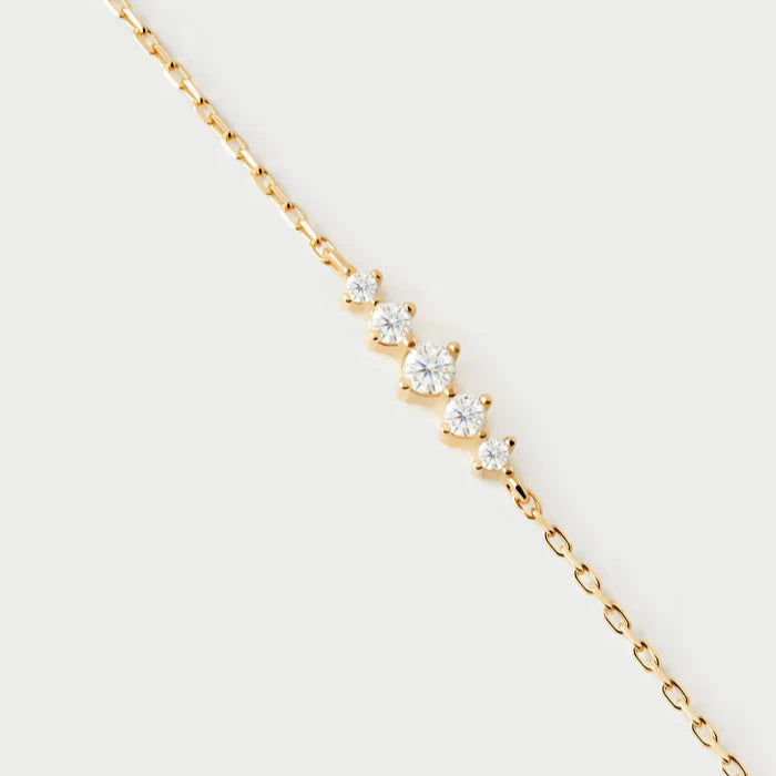 Gold necklace with small diamonds on a light gray background