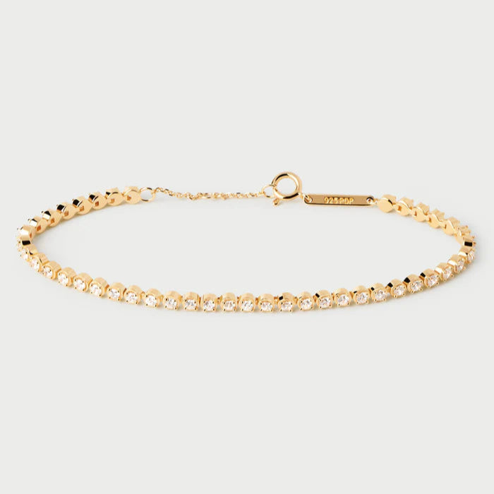 Gold bracelet with clear stones on a light gray background