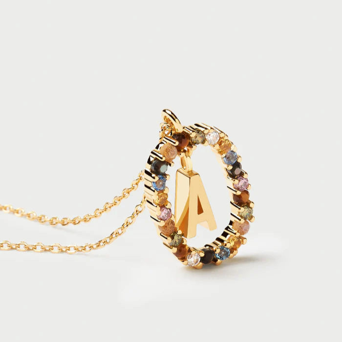 Gold necklace with a multicolored gemstone pendant and letter 'A' on a light gray background