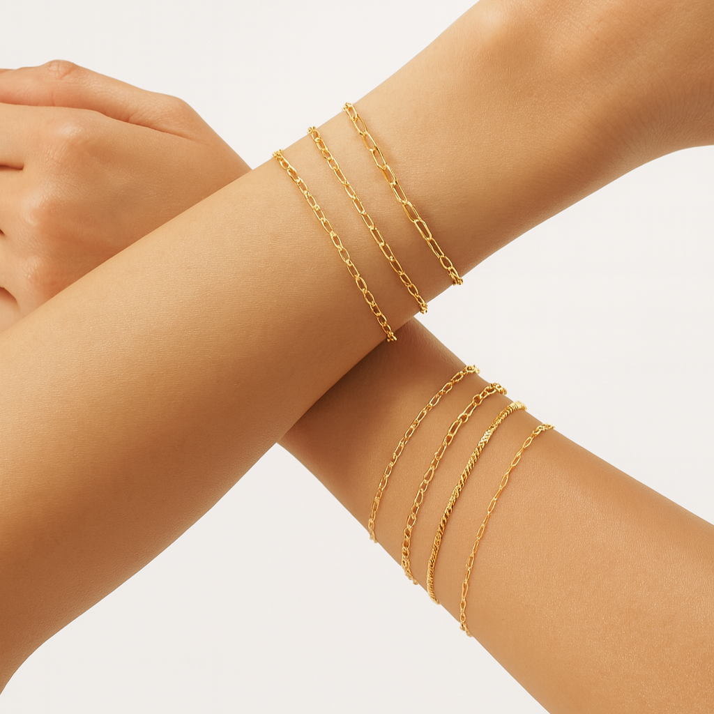 Gold bracelets on a person's wrist against a neutral background