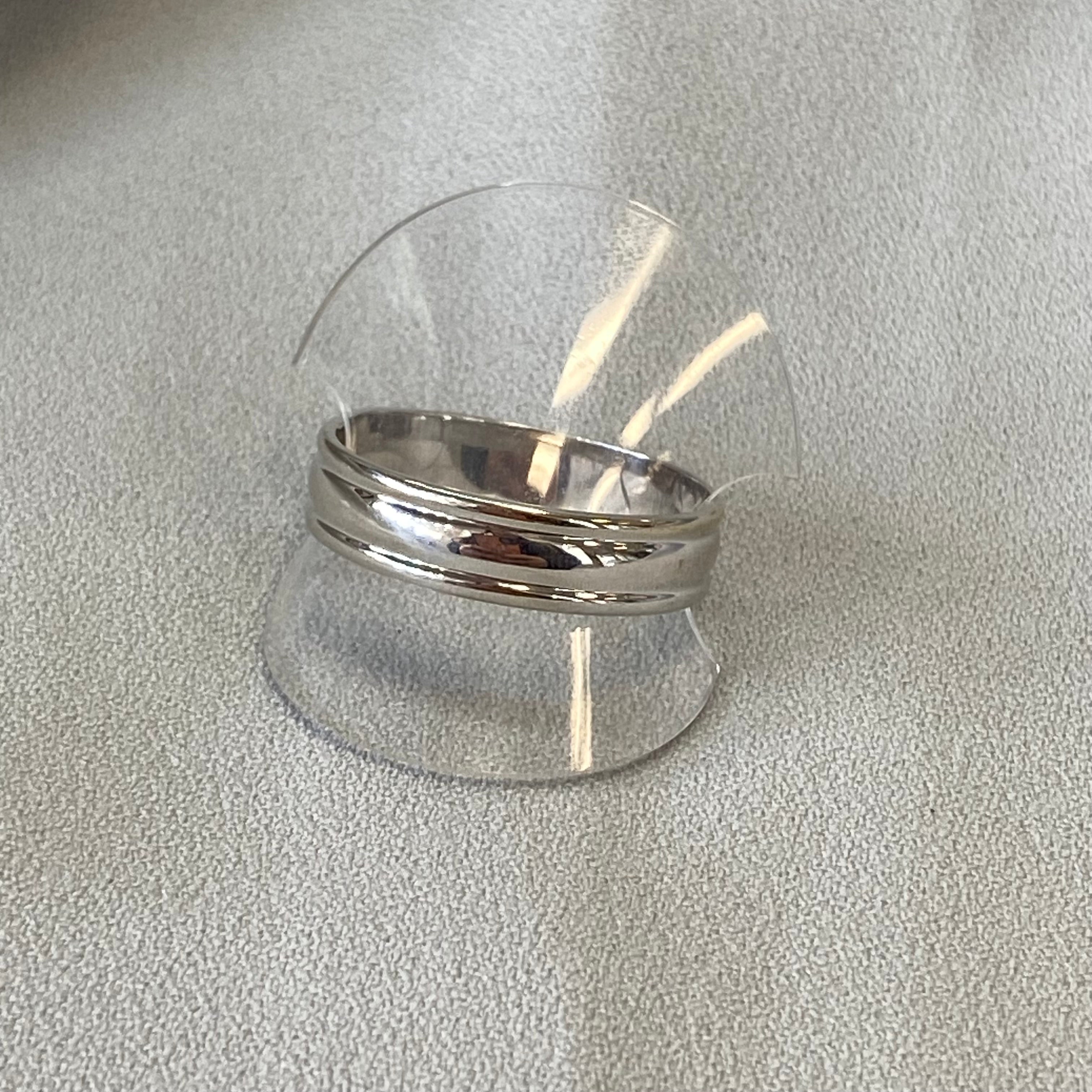 Silver ring inside a clear plastic dome on a gray background