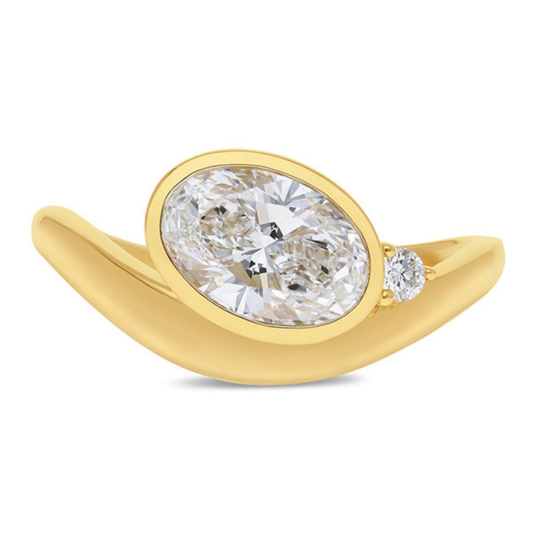 Gold ring with a large diamond and smaller diamond on a white background