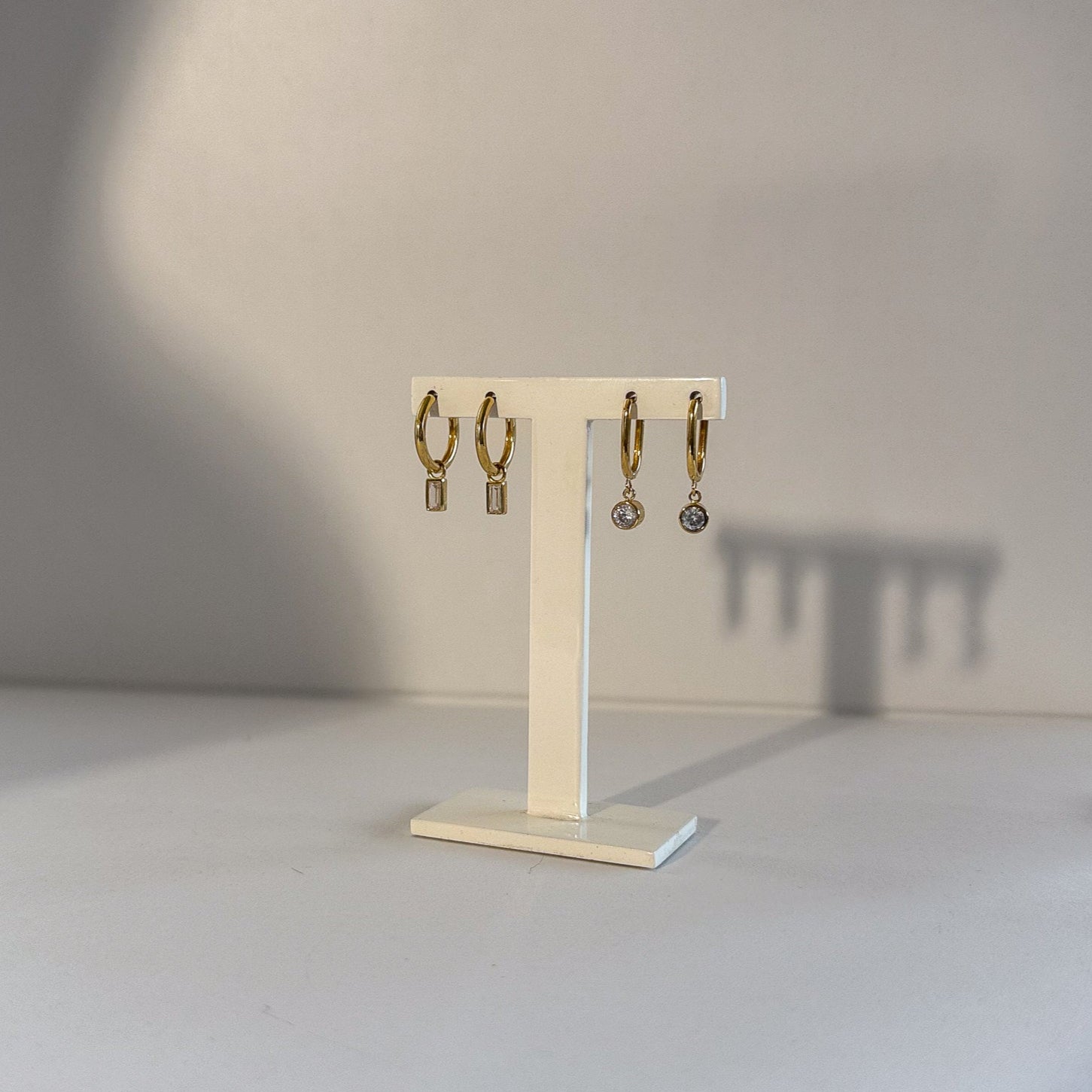 Beige earring stand with hanging earrings on a neutral background