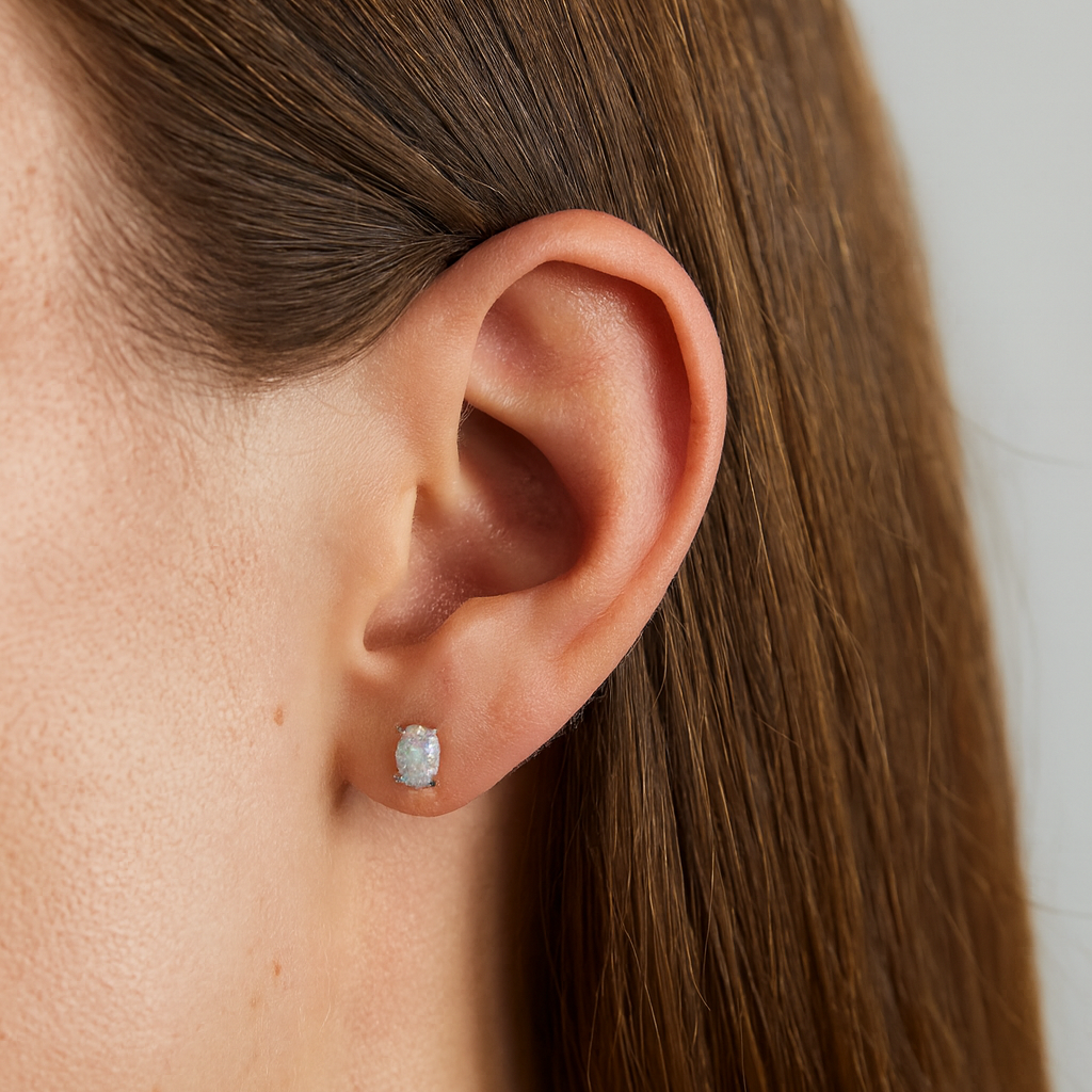 Close-up of an ear wearing a diamond earring with a plain background